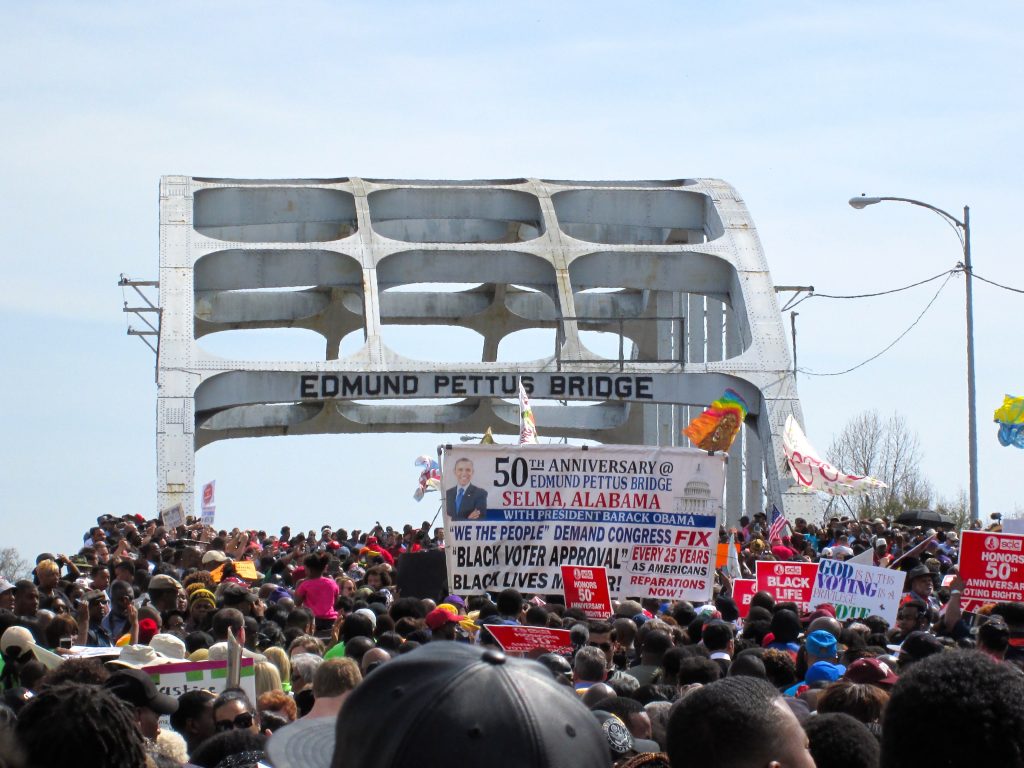 Marchers with signs approaching the Edmund Pettus Bridge in Selma